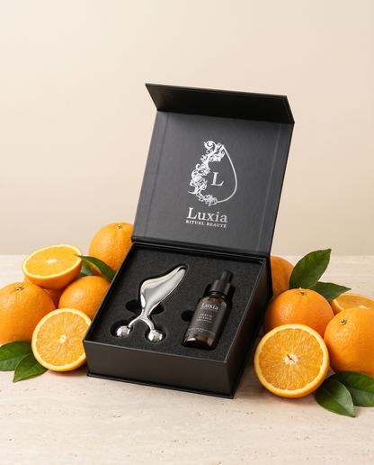 Coffret Duo Gua-sha & Sérum Vitamine C Luxia, entouré d'oranges
